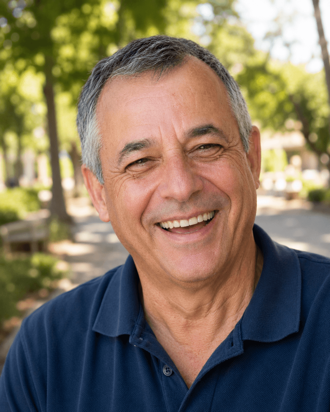 Smiling man with grey hair in a navy polo shirt